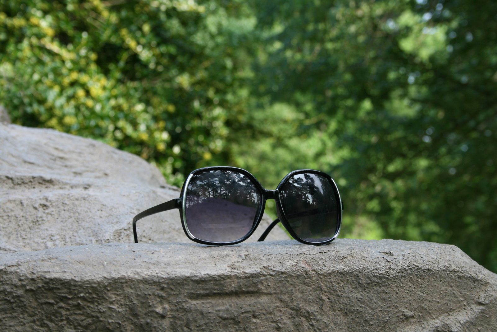 A pair of sunglasses with dark lenses resting on a flat surface