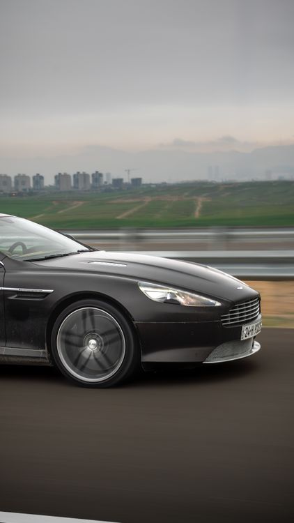 A sports car driving on a highway under a cloudy sky
