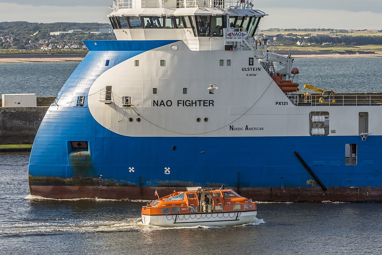 Passengers in orange life jackets during a cruise ship safety drill