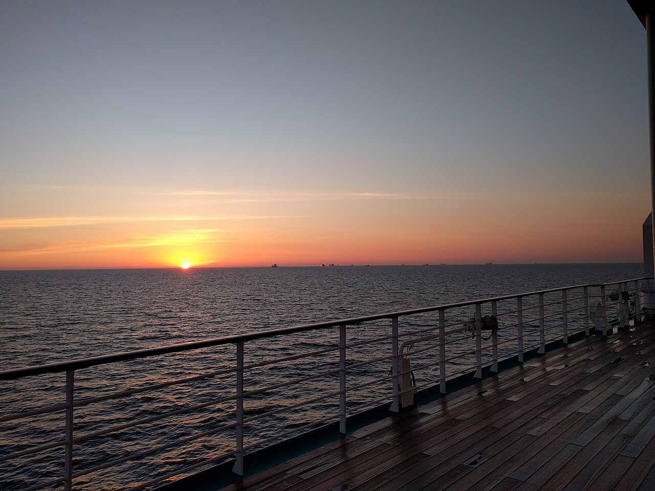 A cruise ship at sunset with decks and lifeboat stations visible
