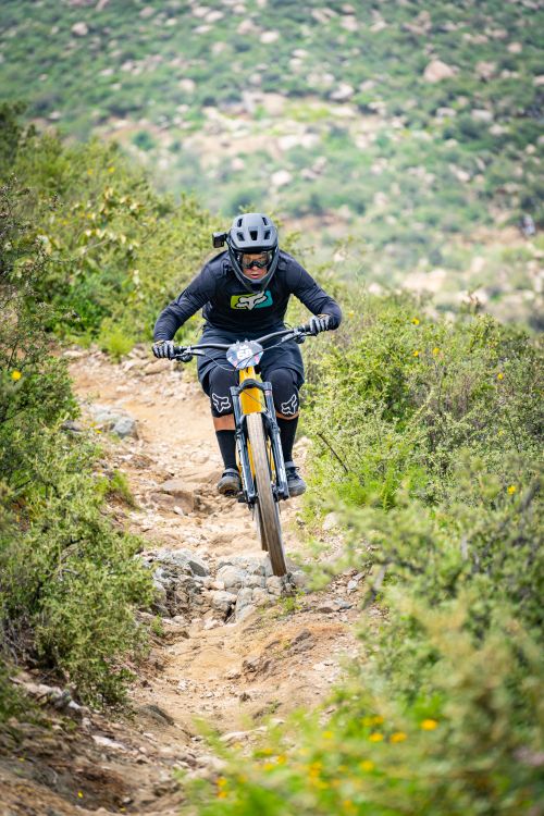 A cyclist riding a rugged mountain trail on a full suspension bike