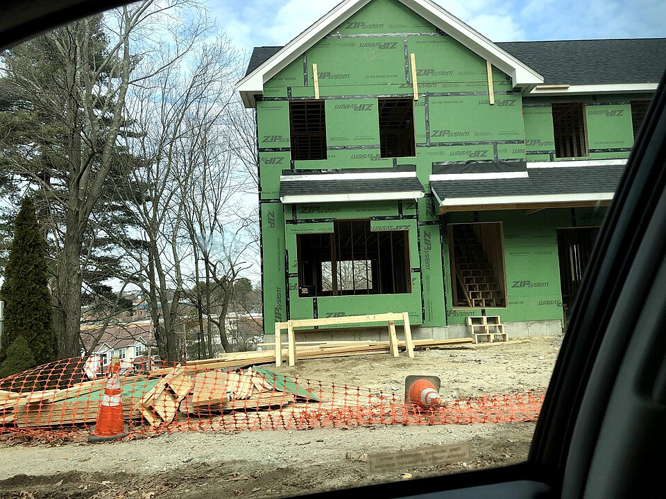 Wall framing underway on a new house, with studs visible before sheathing