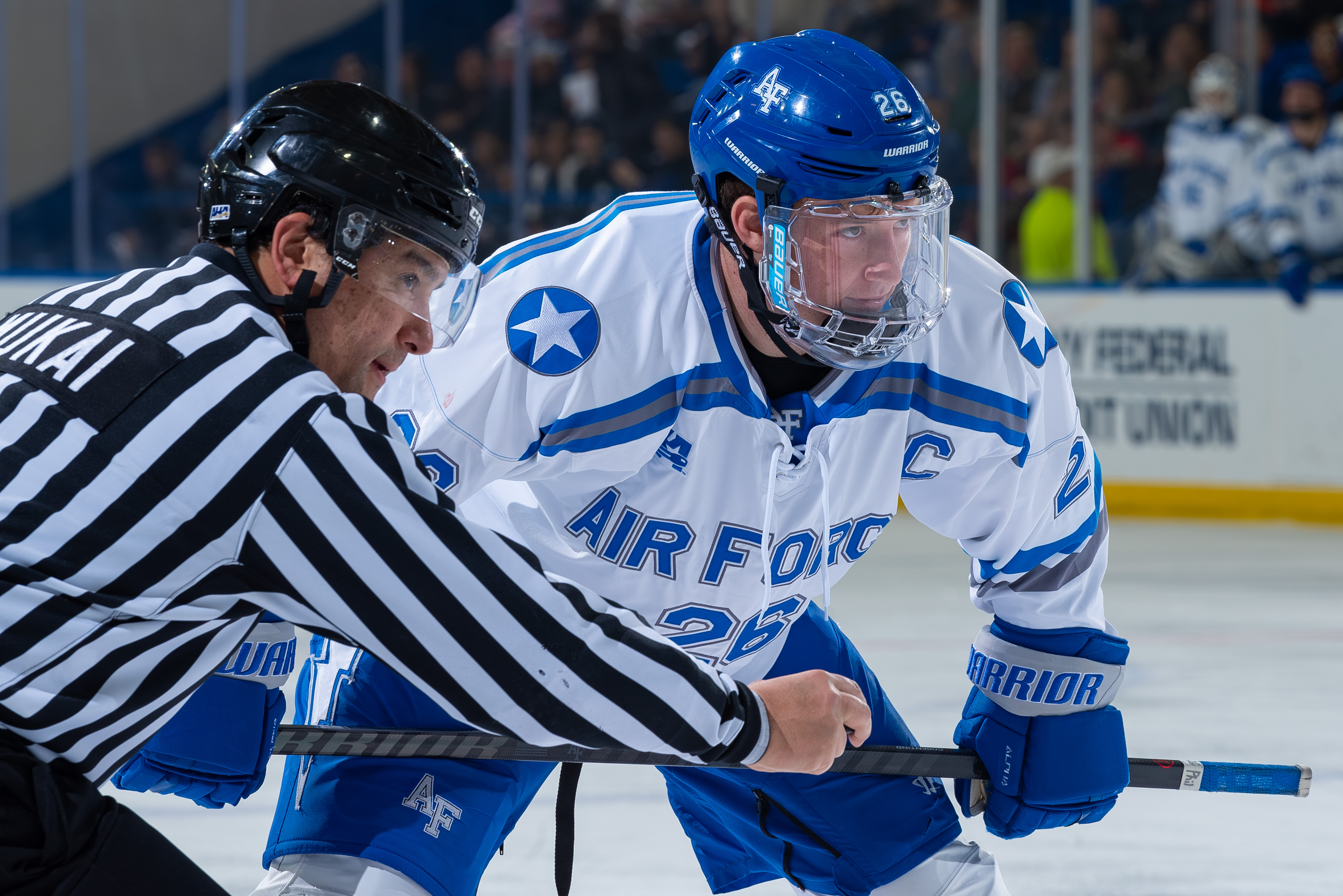Two players battle for the puck at a face-off in an ice hockey game