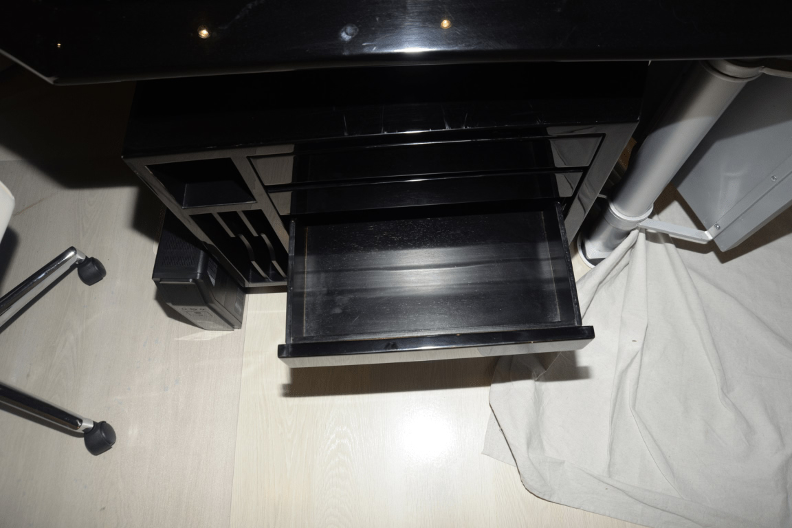 An empty office desk with an open drawer beside a rolling chair
