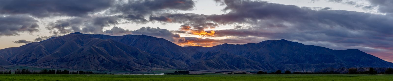 Sunrise over a mountain range, with warm light spreading across the peaks