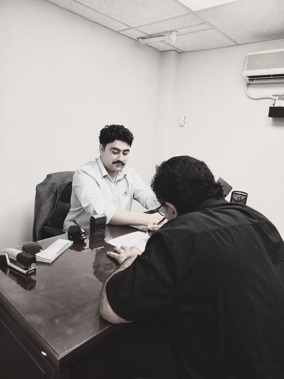 A notary assisting a client signing documents at a desk