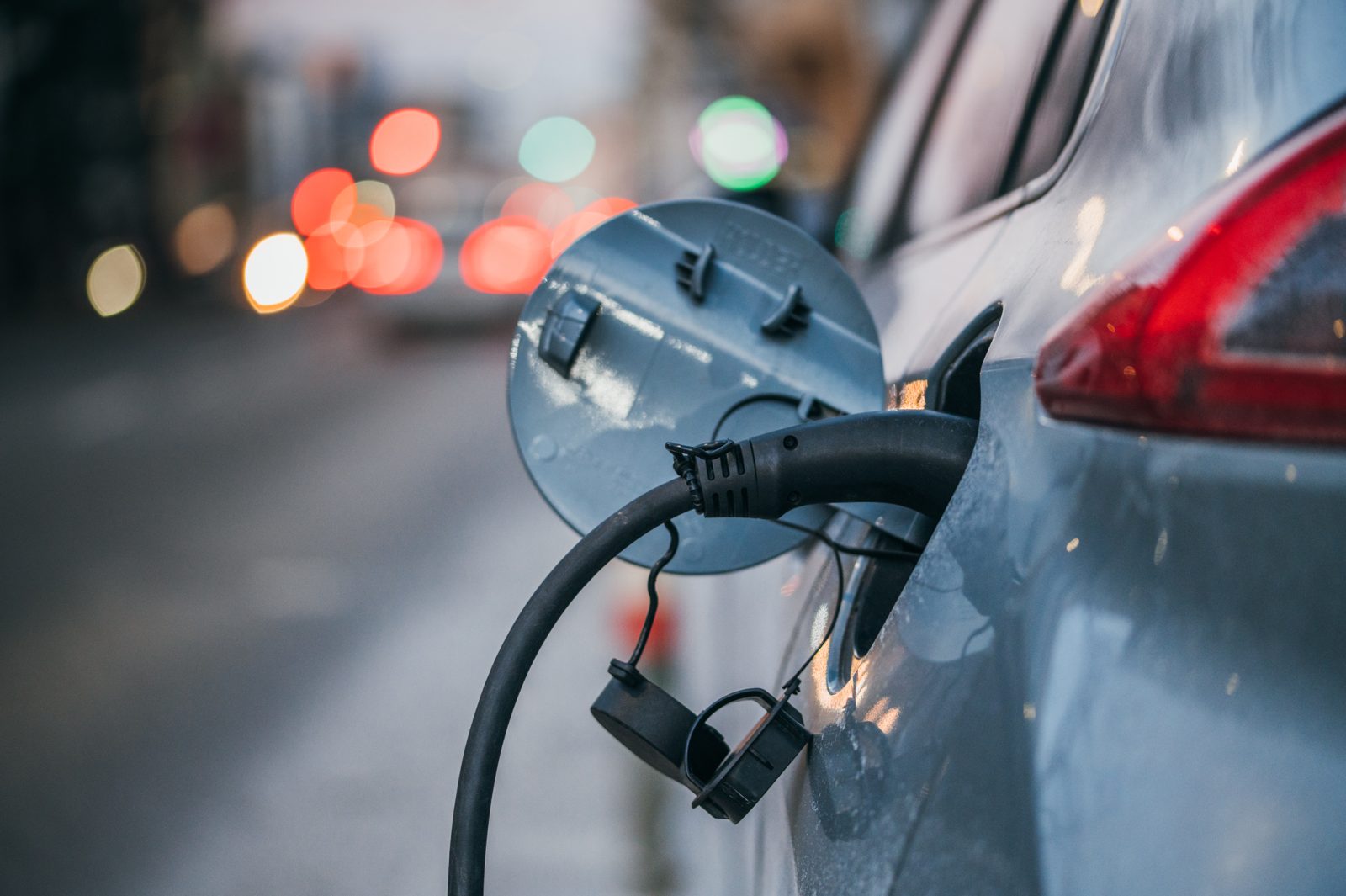 Close-up of an electric car charging, with a charging cable plugged into the car