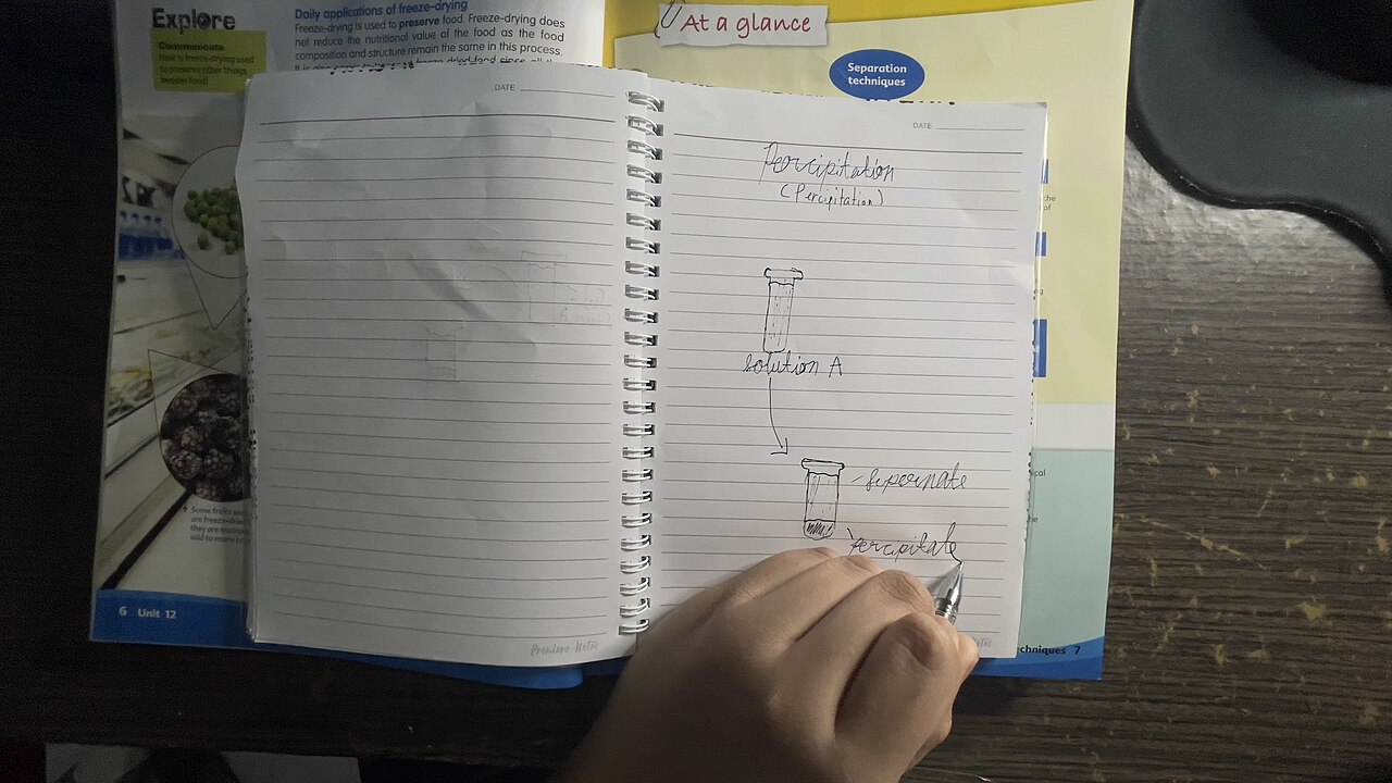 A hand writing notes in an open notebook
