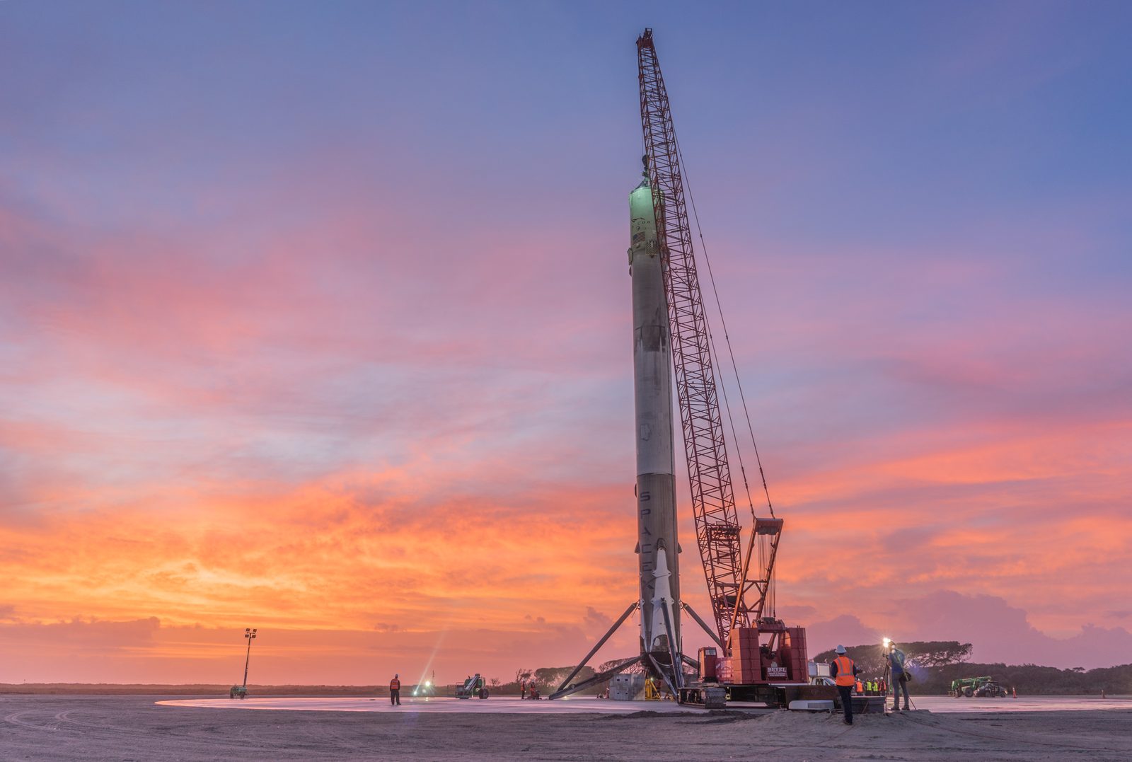 A Falcon 9 booster stands on a landing zone after landing