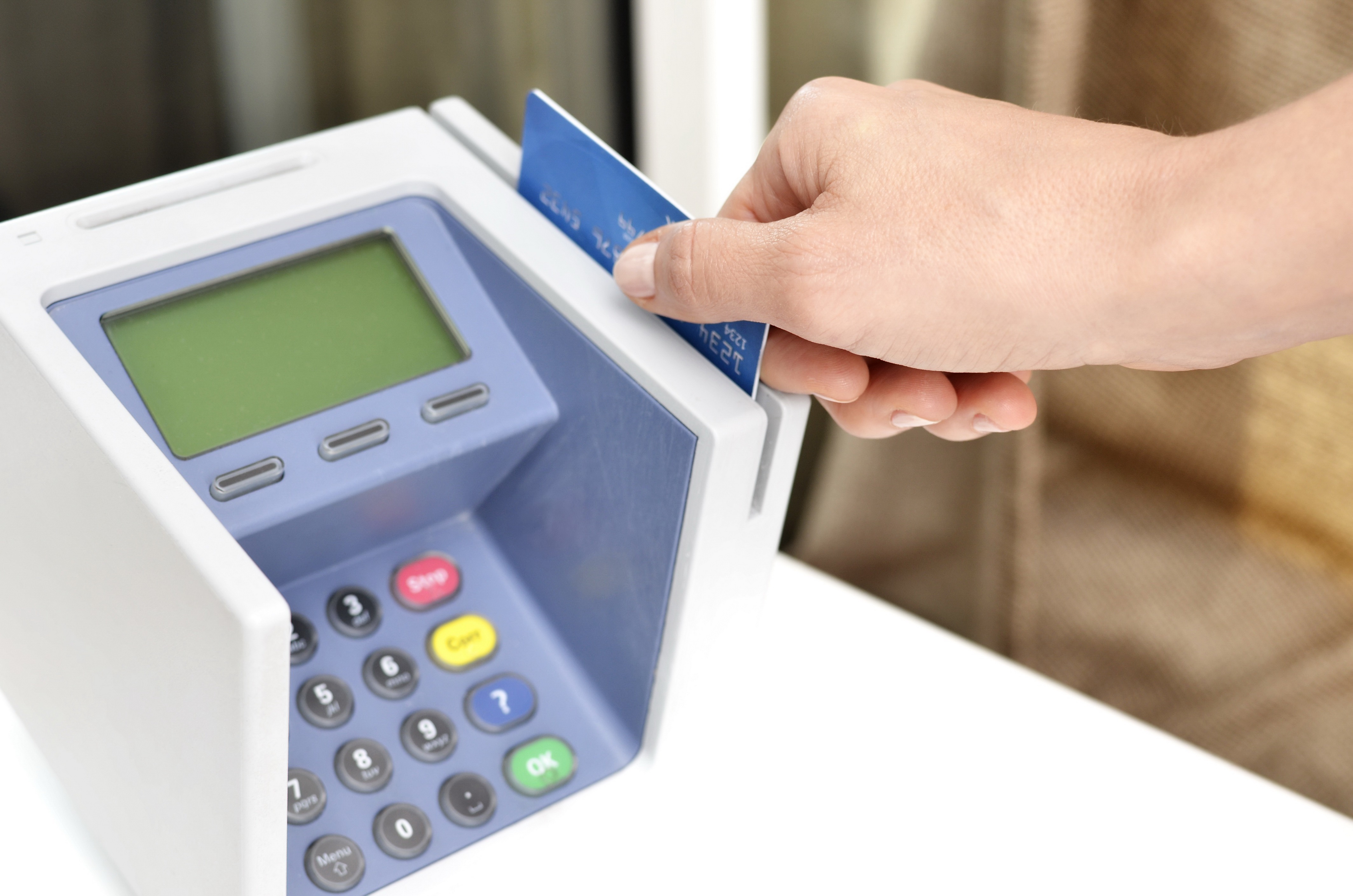 A shopper paying with a credit card at a checkout counter