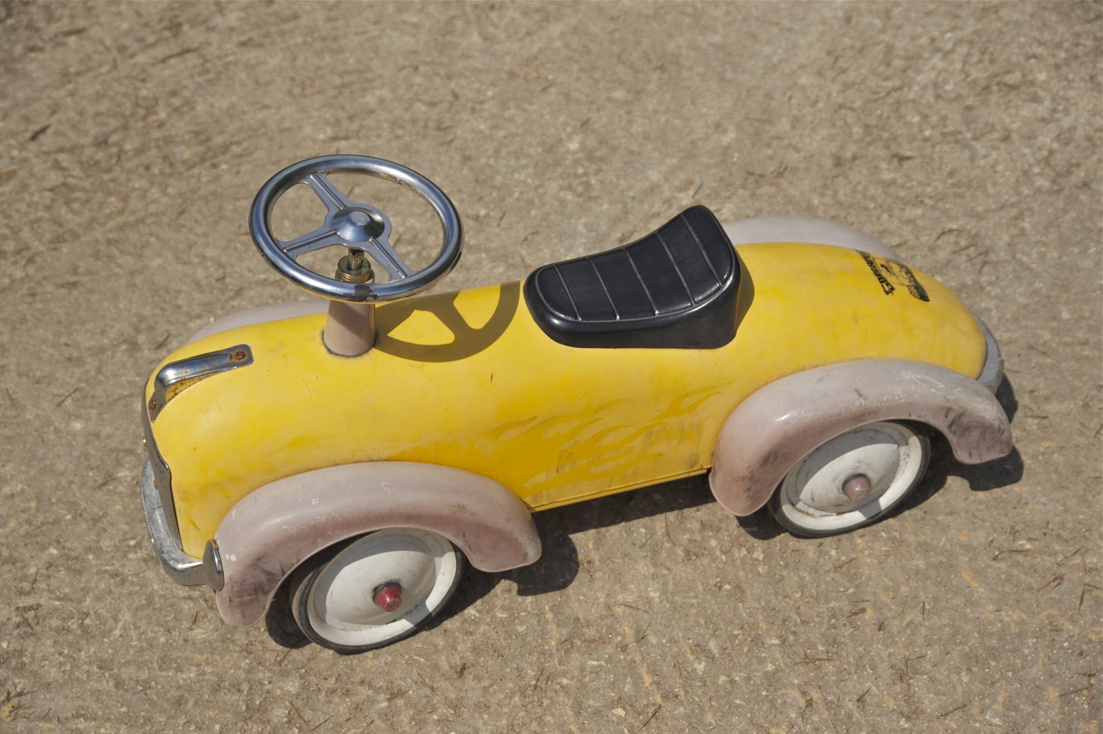 A yellow toy car on a plain surface