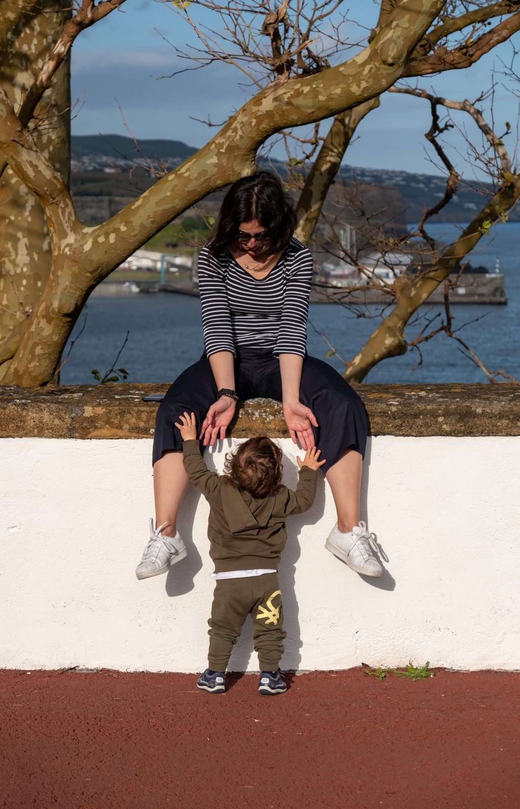A mother and toddler walking together in a park
