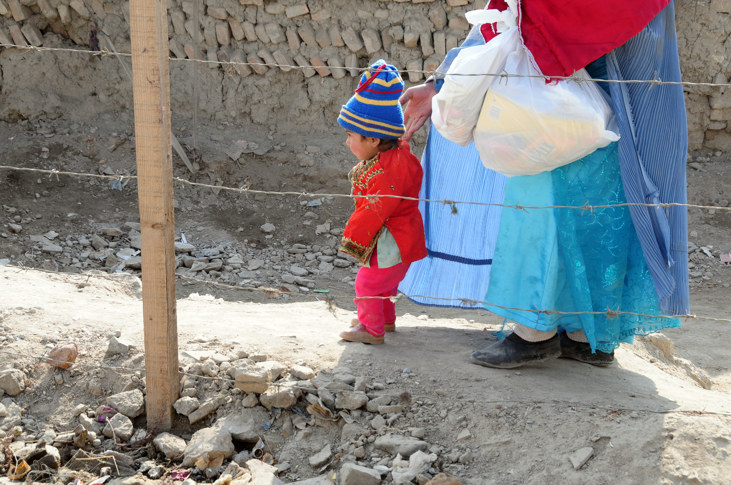 A toddler walking beside a parent on a path