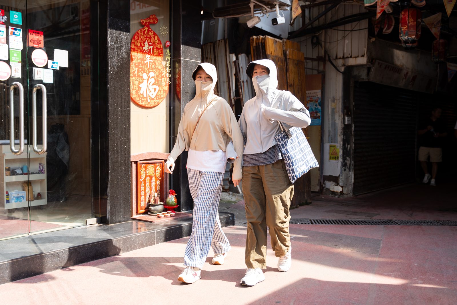 Two women wearing sun-protective clothing, hats, and sunglasses during a heatwave