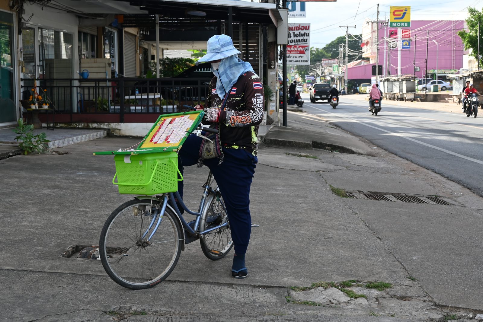 A street vendor wearing sun-protective clothing and a wide-brimmed hat