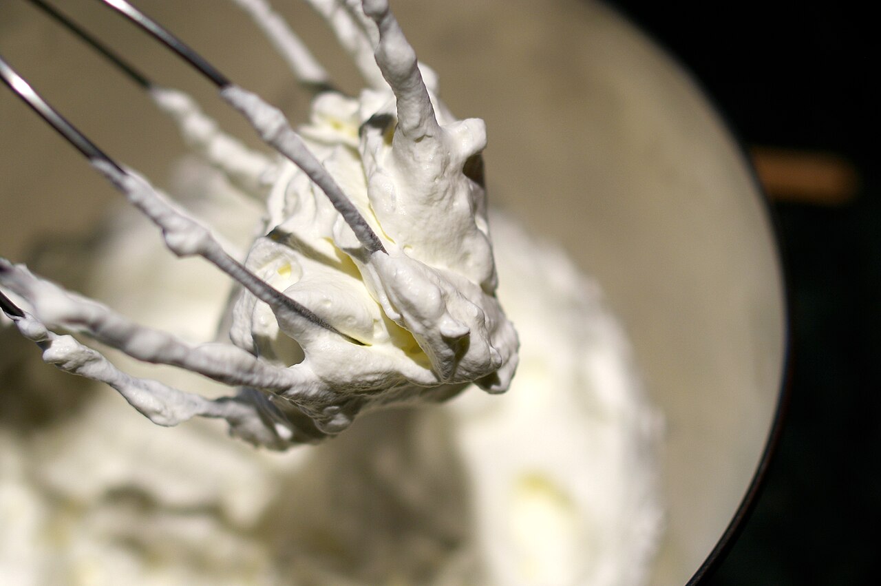 A bowl of freshly whipped cream with soft peaks