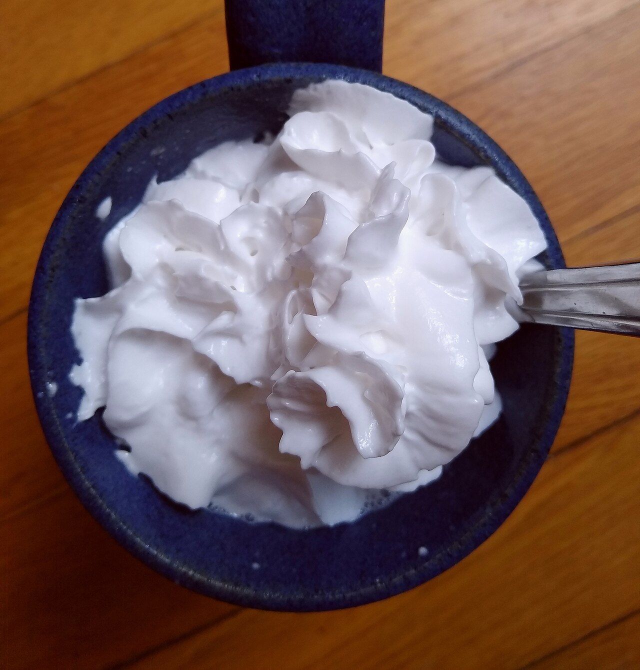A small bowl of whipped cream beside a dessert