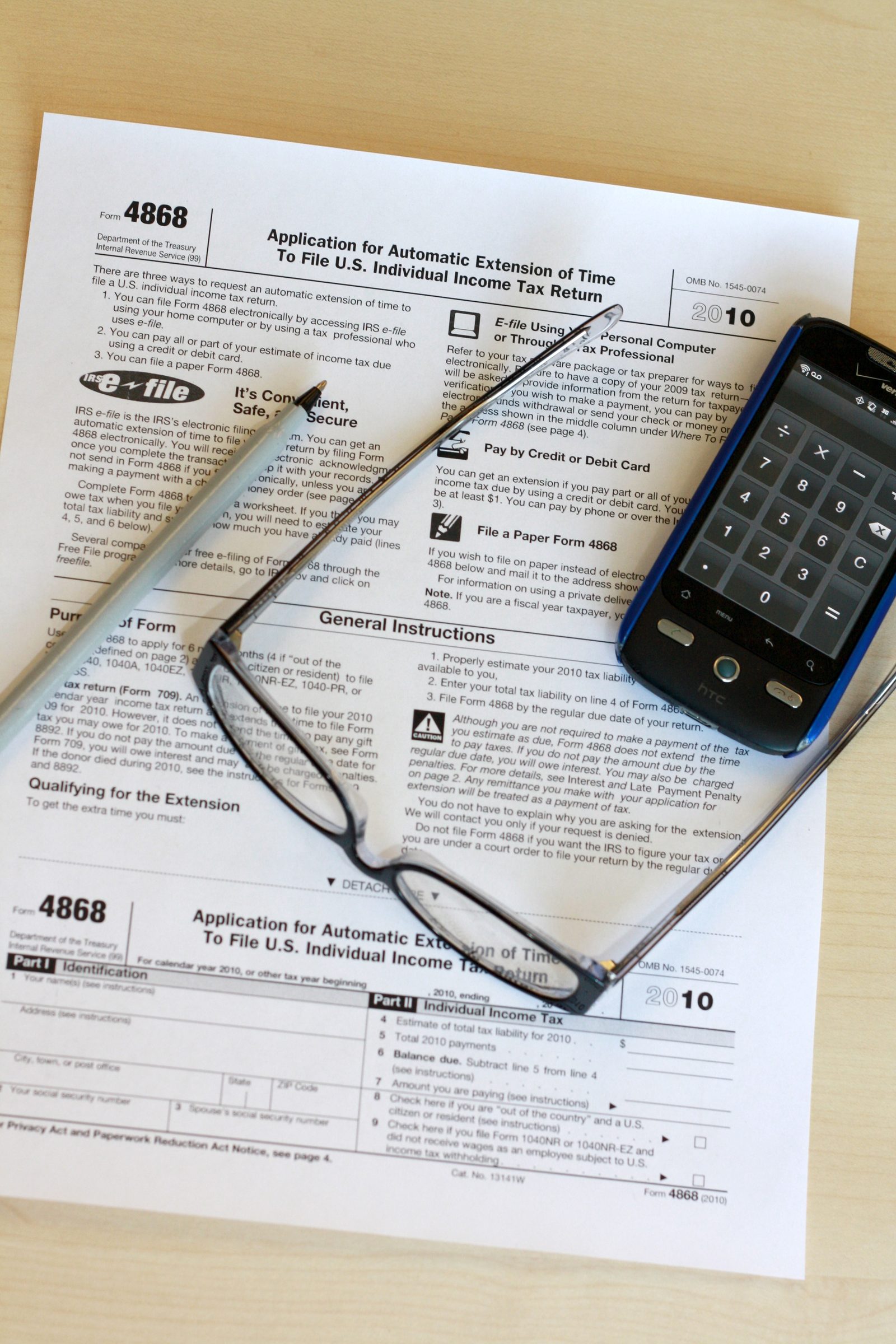 A tax form with a pen, glasses, and a phone