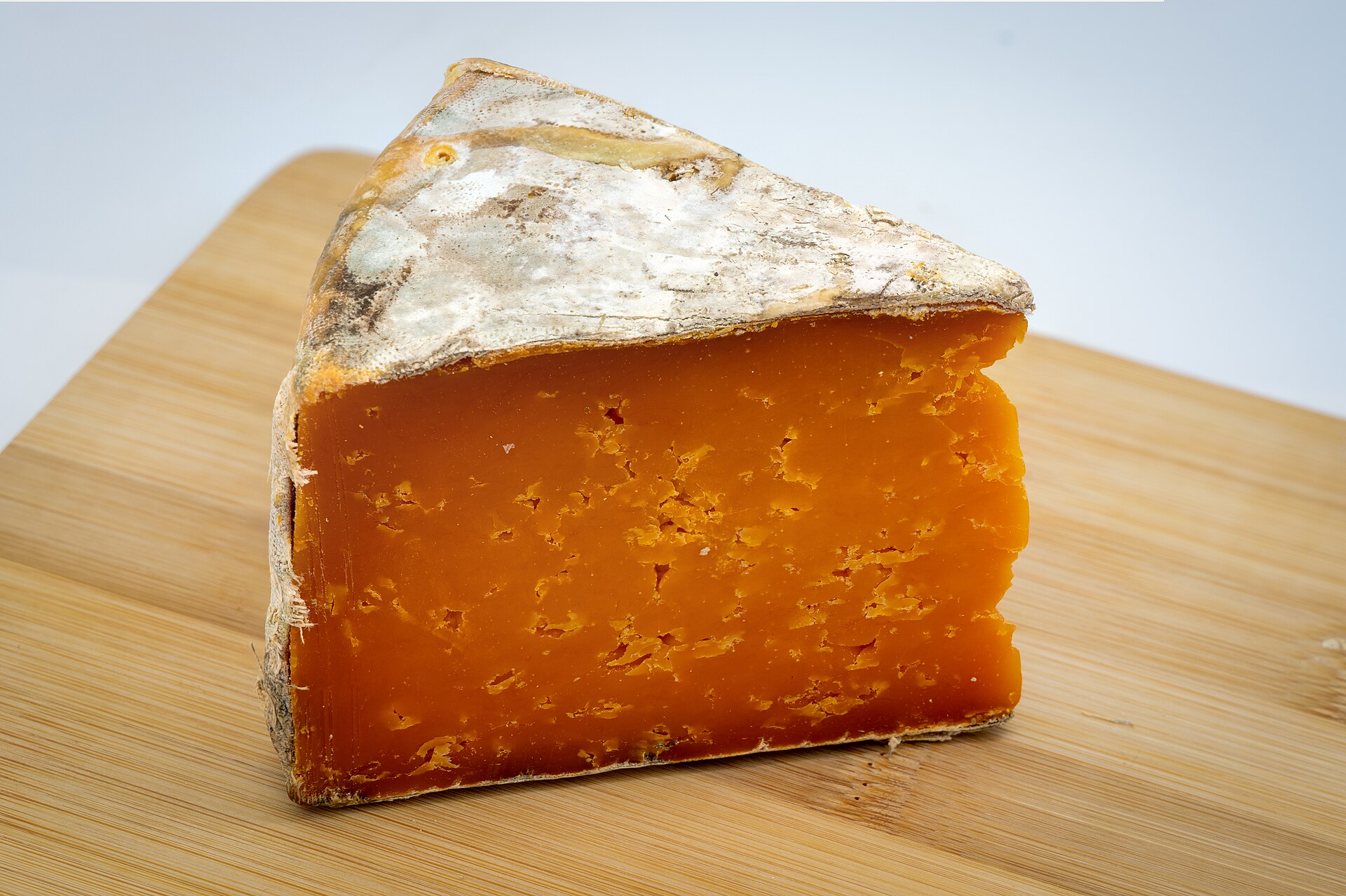A wedge of cheddar cheese on a board