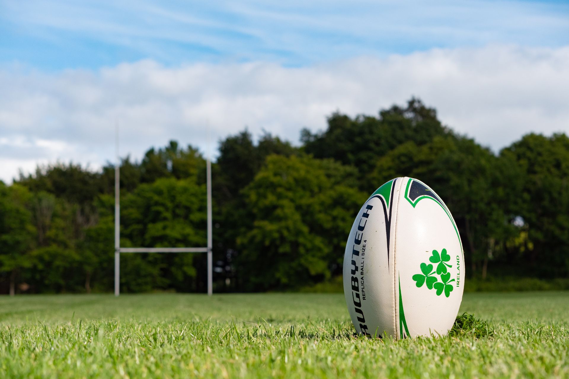 A rugby ball rests on green grass on a pitch