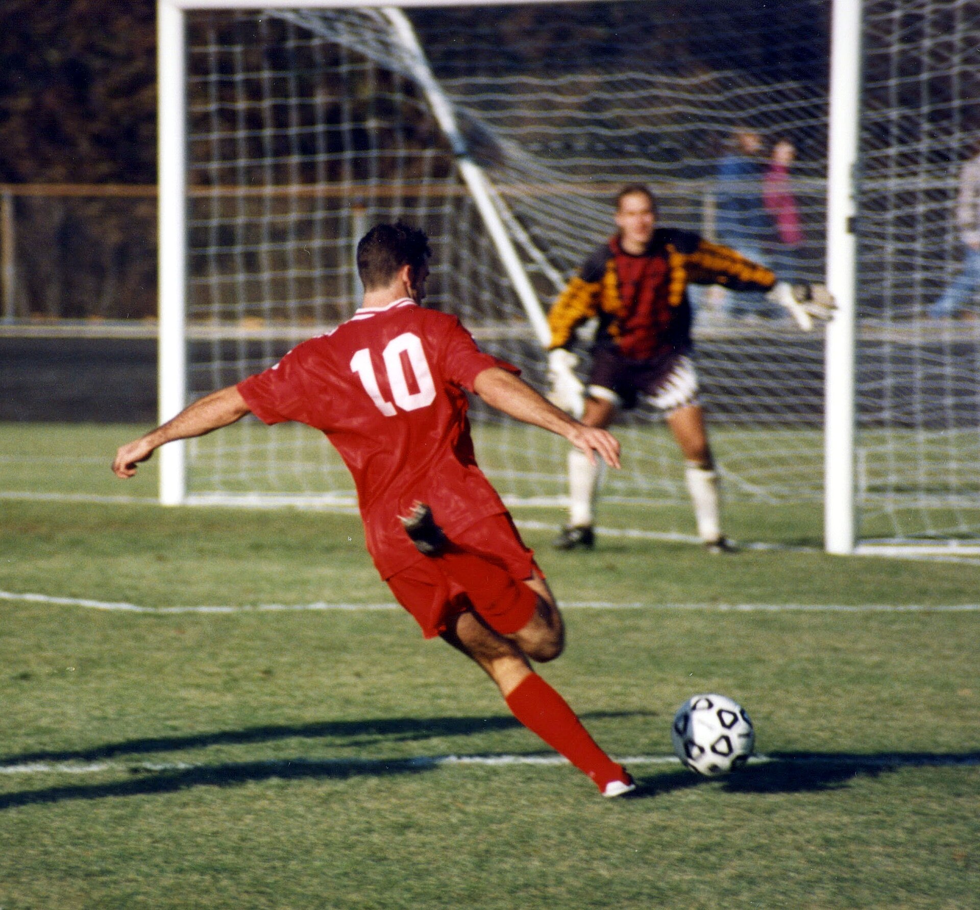 Two players play soccer on a grass field