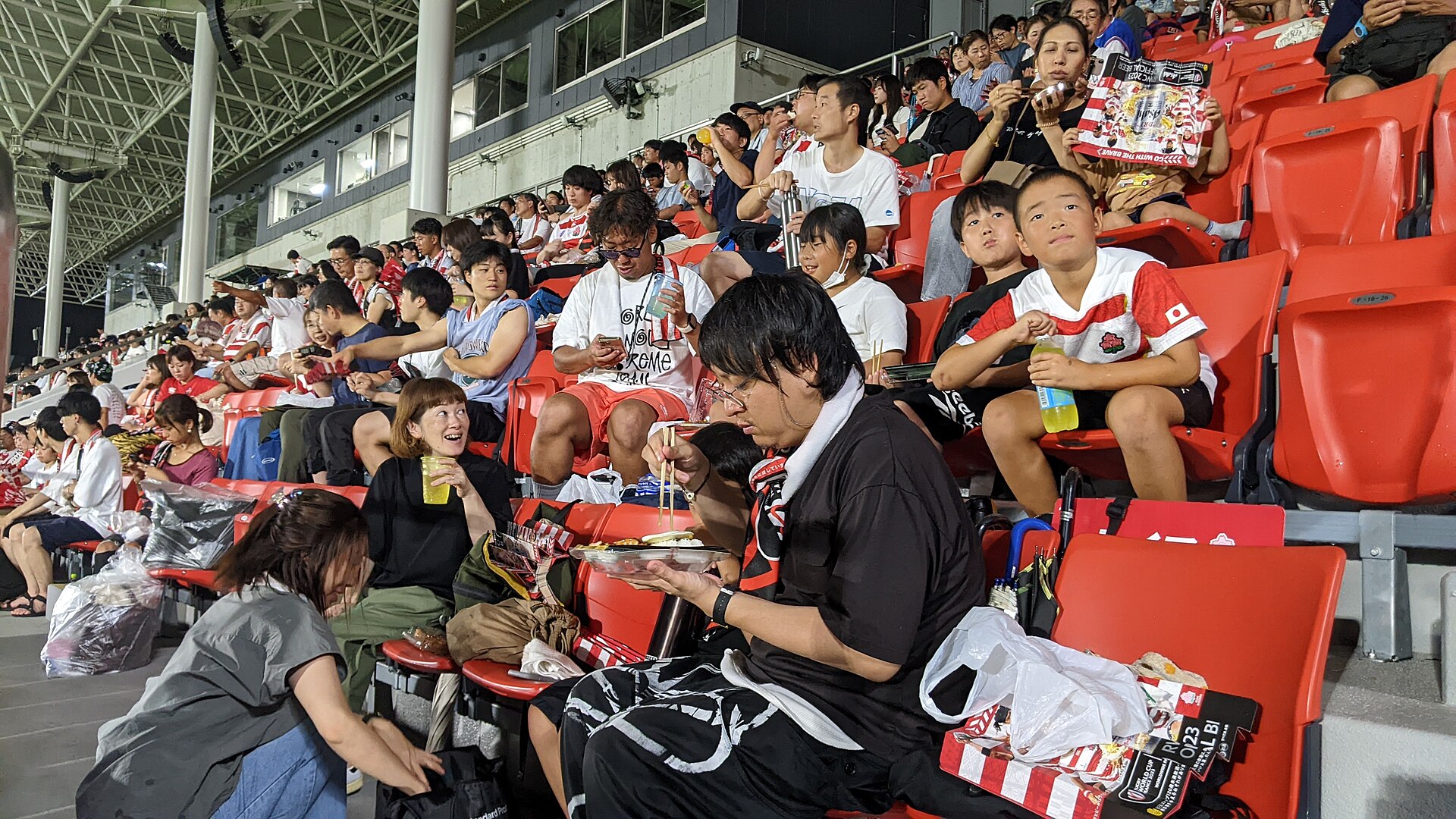 Fans watch a rugby match on a big screen at a stadium