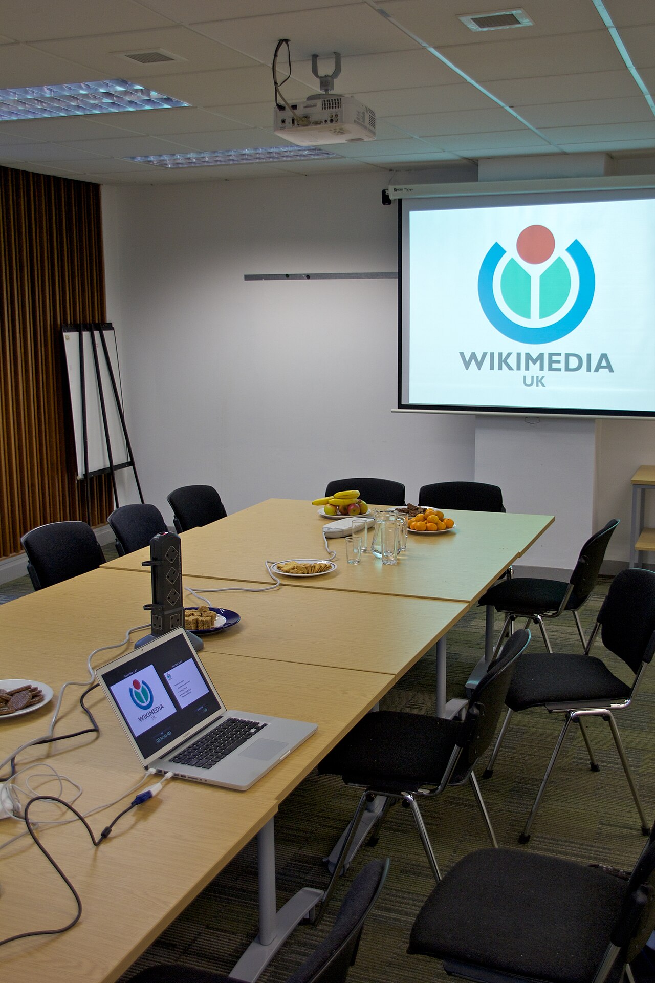 An empty meeting room set up with a laptop and a projector screen