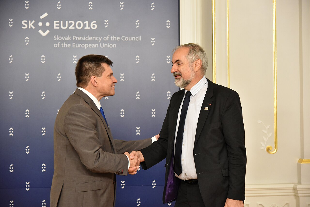 Two men in suits shaking hands at a formal meeting