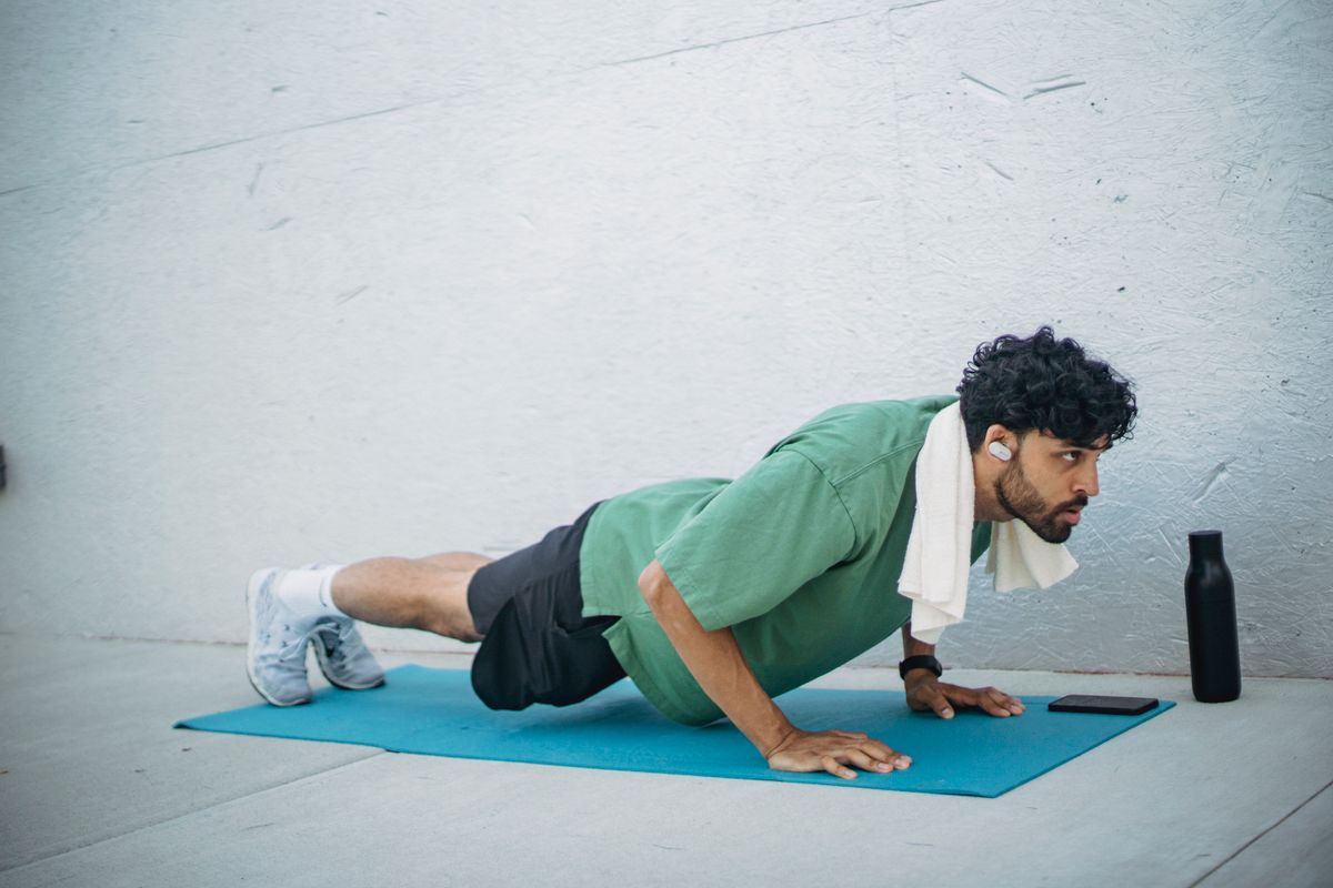 A man doing push-ups on a yoga mat at home
