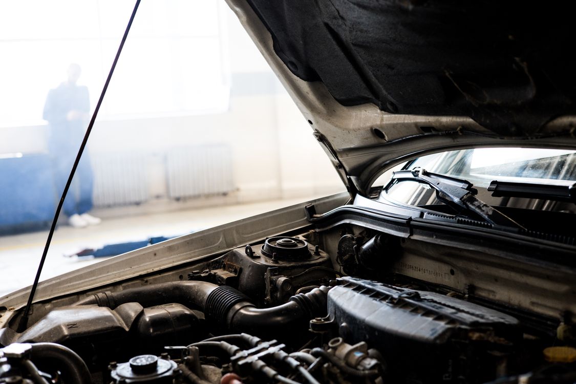A car engine under an open hood in a garage