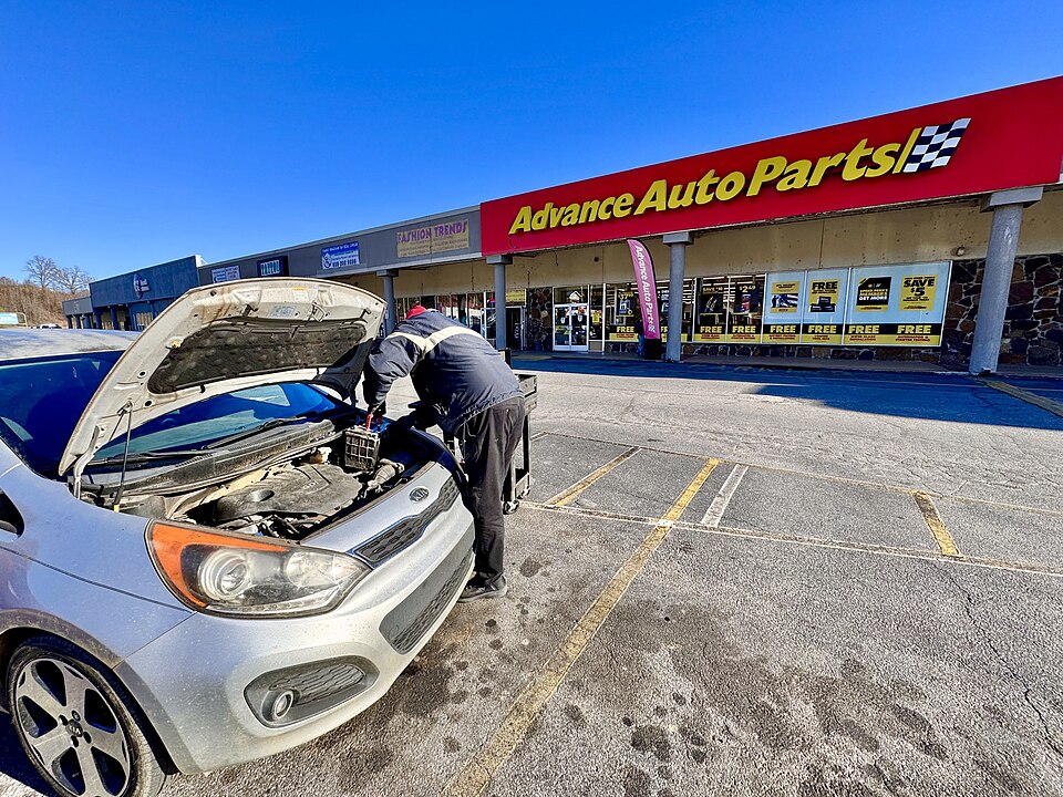 An employee changing a car battery in a parking lot