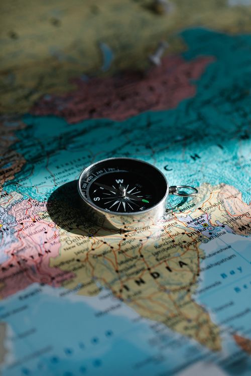 A close-up of a compass resting on a map of India
