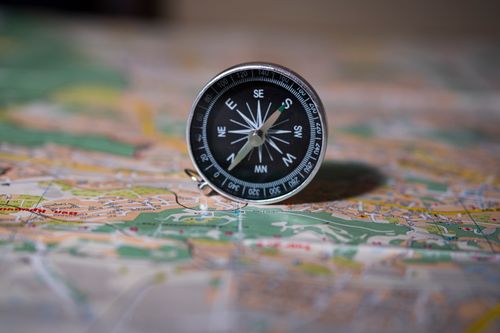 A black compass on a detailed map, showing the tool used with a chart