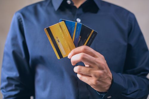A person holds three credit cards, showing the revolving accounts that feed a credit score