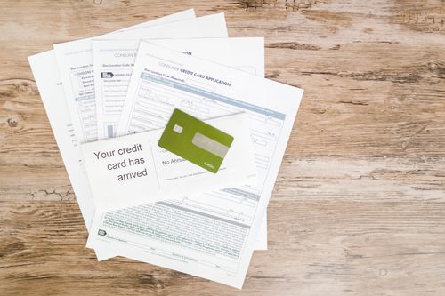A top view of a credit card and application documents on a wooden surface