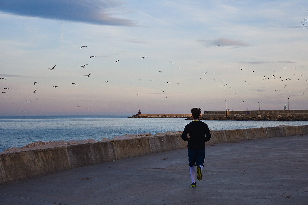 A person jogging along a seafront promenade