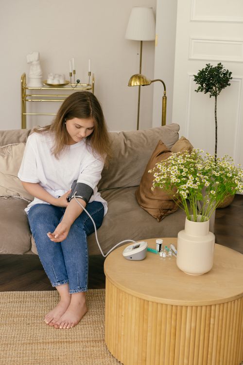 A woman checks her blood pressure at home with an arm cuff monitor