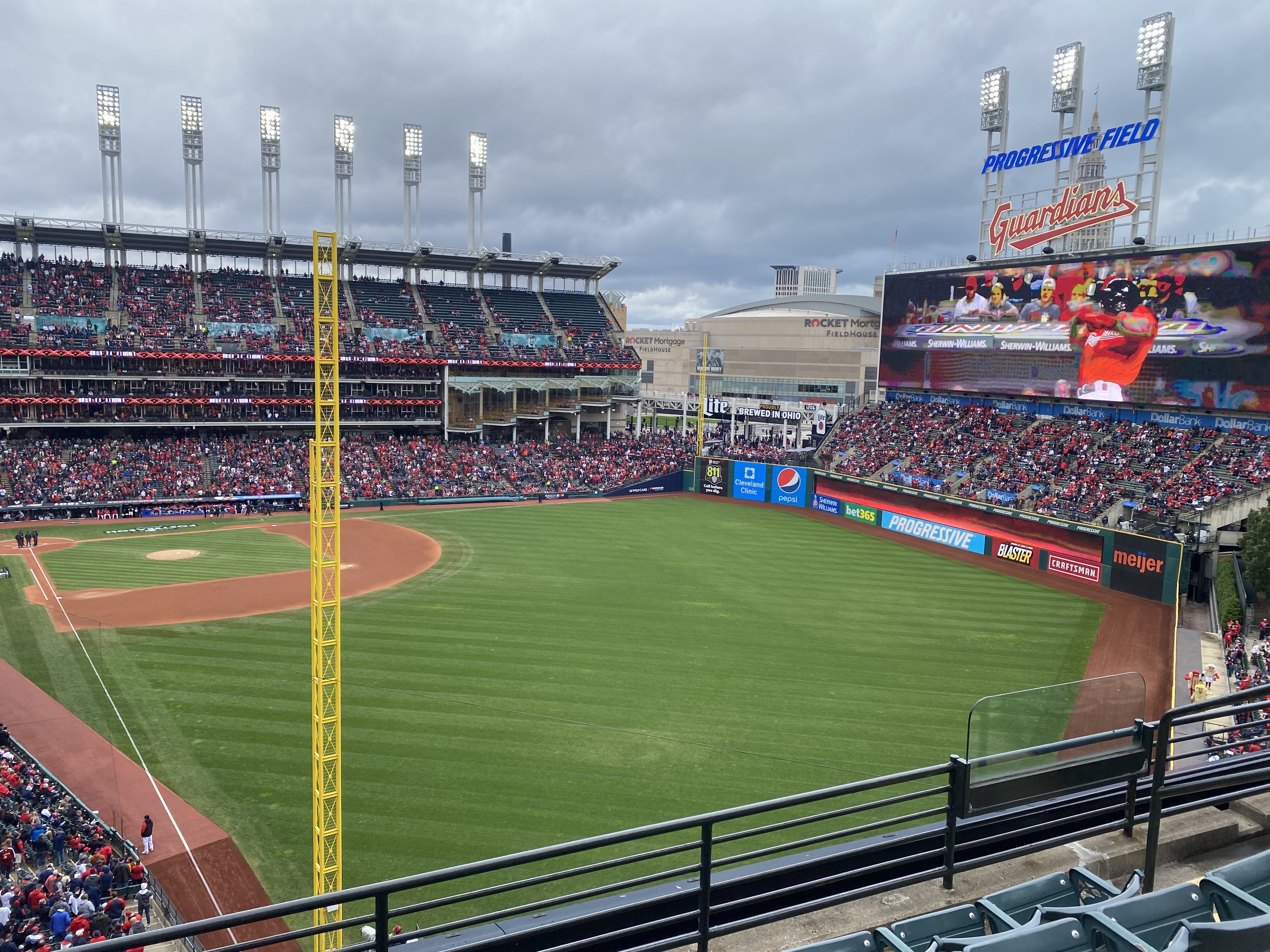Progressive Field in Cleveland under a cloudy sky, with Guardians signage on the scoreboard