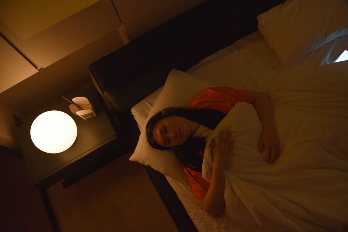 A woman lying awake in bed under dim lighting at night