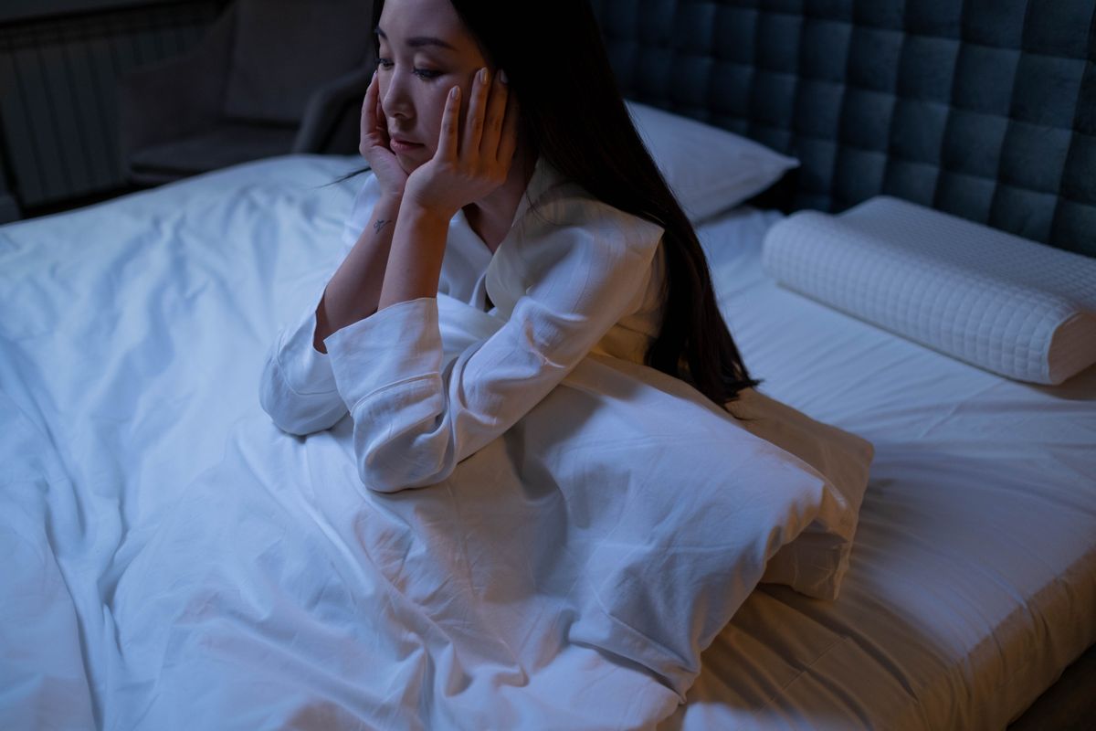 A woman sitting up in bed at night, deep in thought