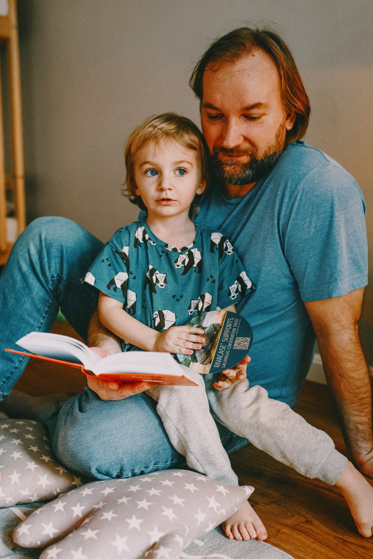 A father reading a book to his young son at home