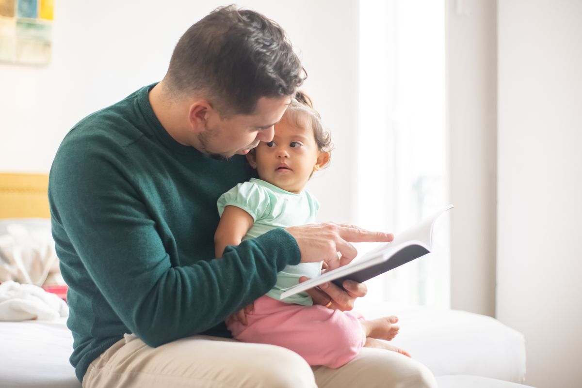 A father reading a book to his daughter at home