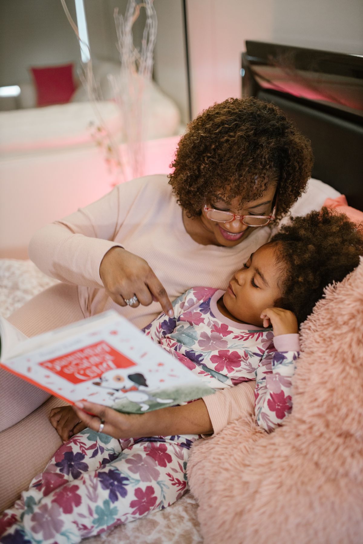 A mother reading a book to her daughter in bed