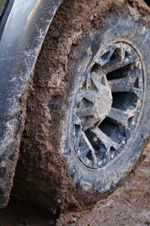 A mud-covered off-road tyre showing heavy tread wear