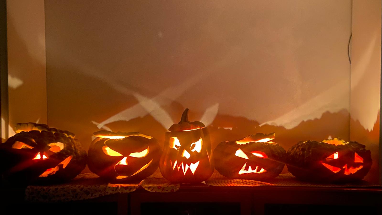 Five carved pumpkins glow at Halloween