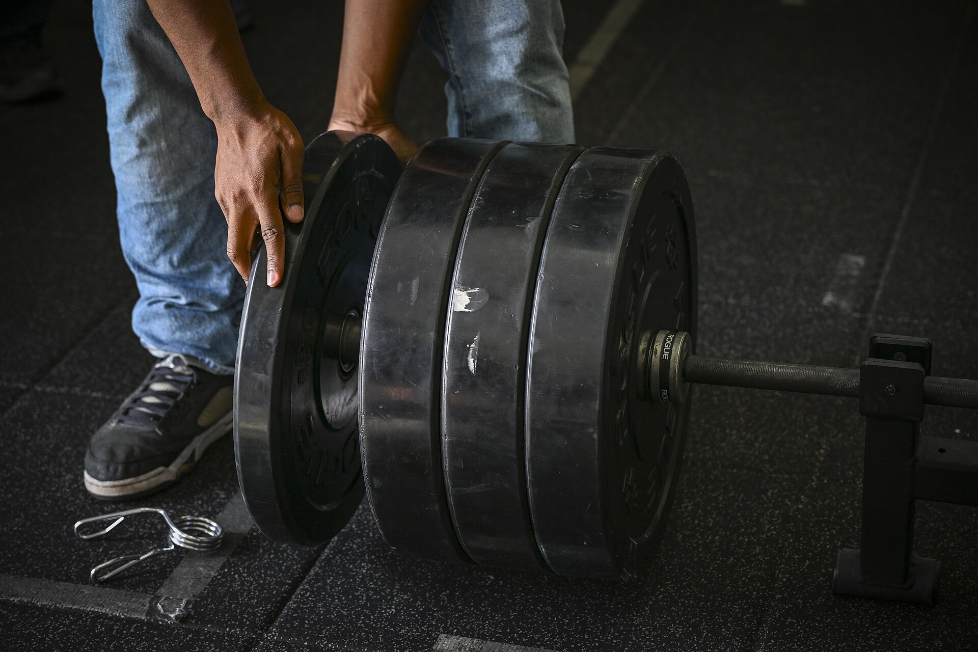 Hands loading weight plates onto a barbell