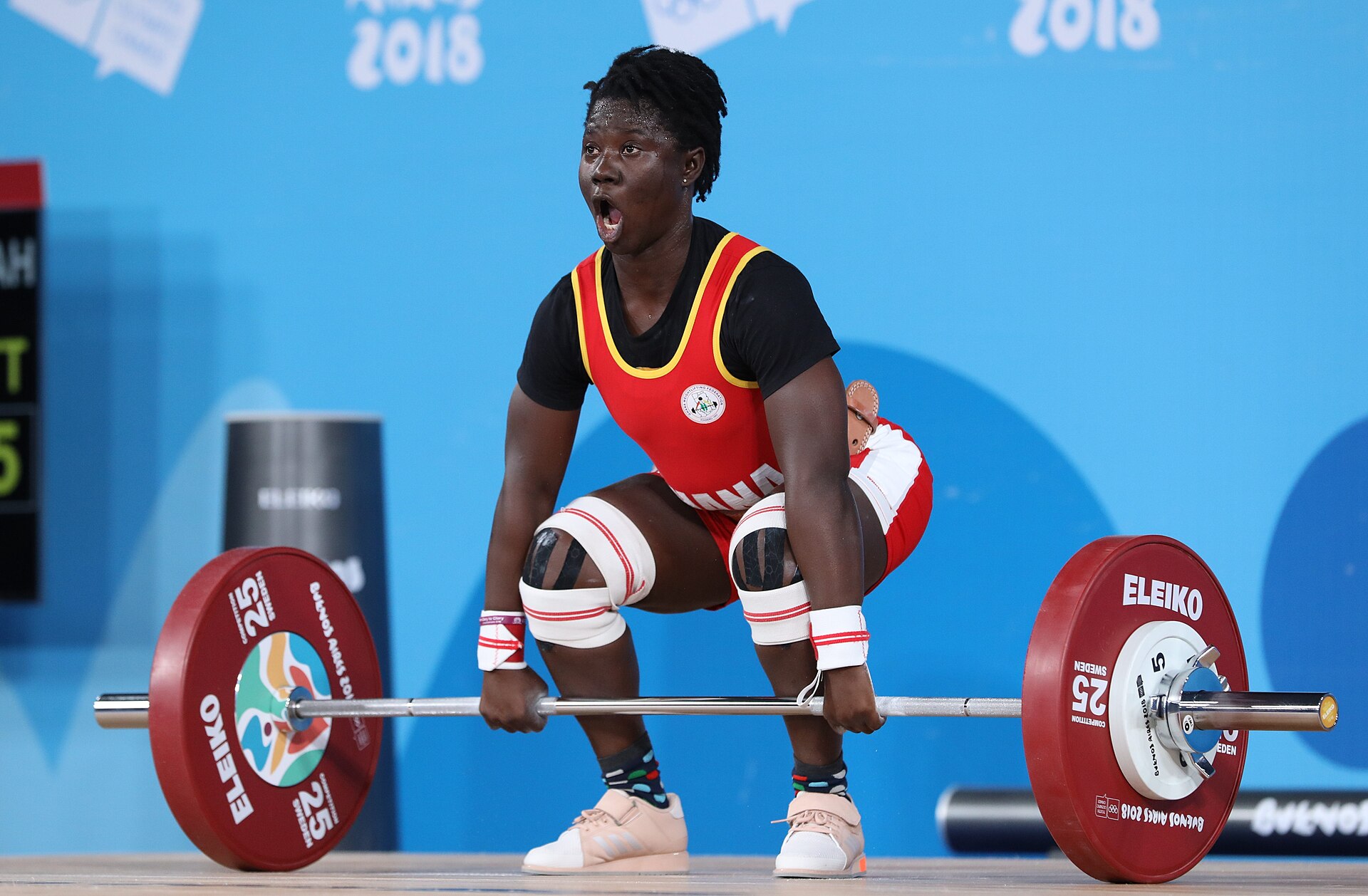 A weightlifter lowering into a deep squat with a barbell