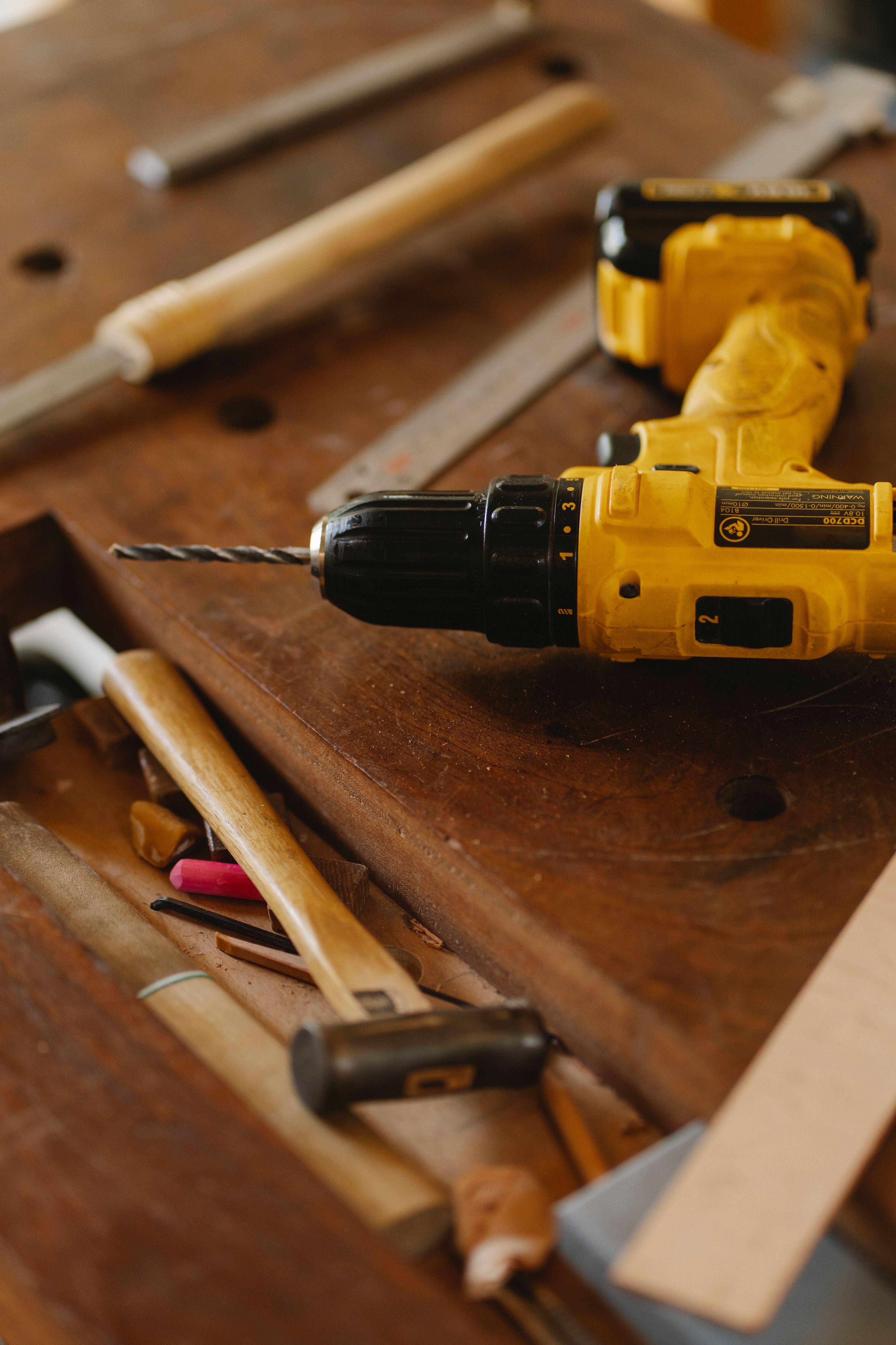 A screwdriver drill among carpentry tools on a workbench