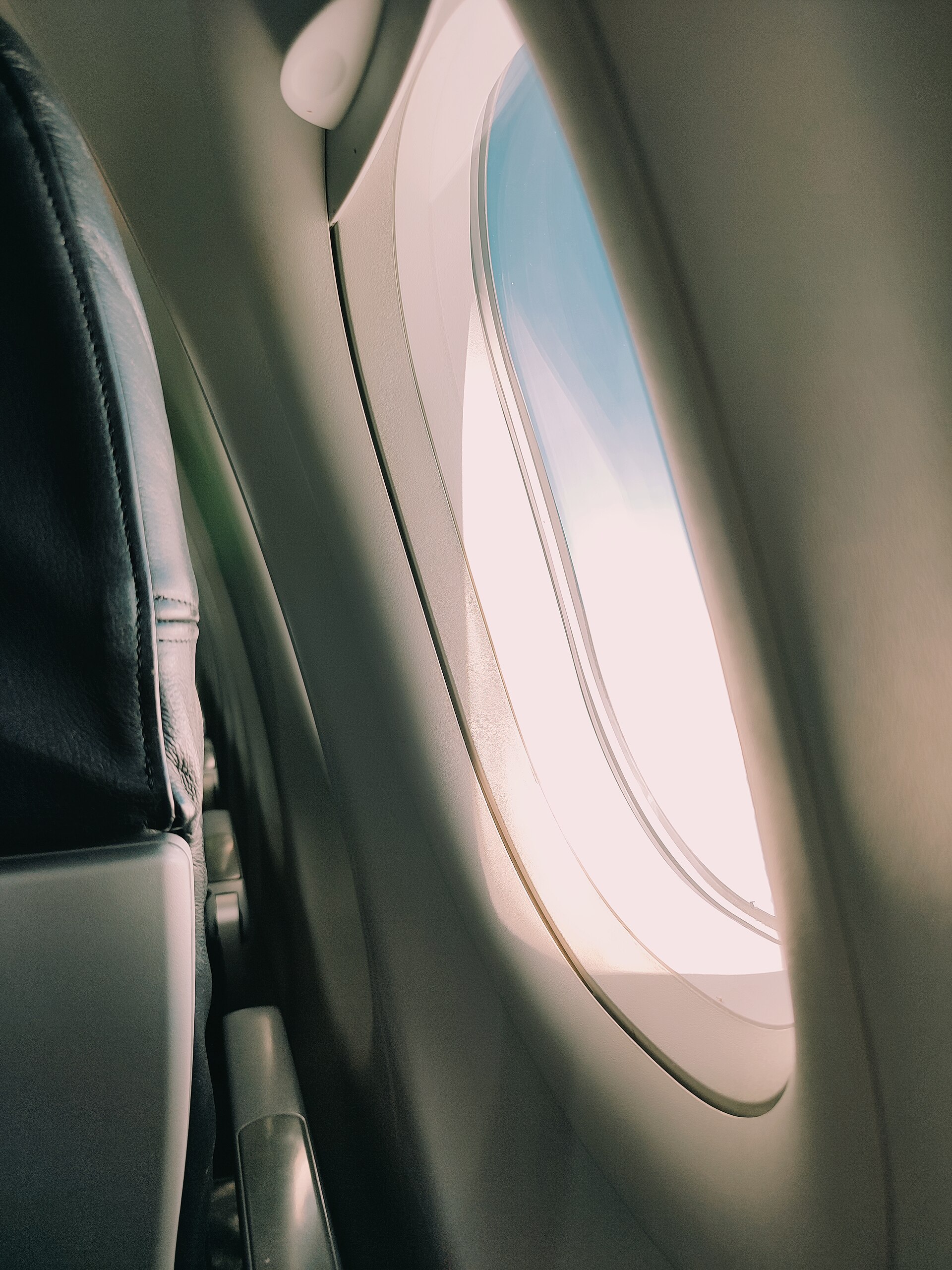 An airplane passenger seat beside a window, with the wing visible outside