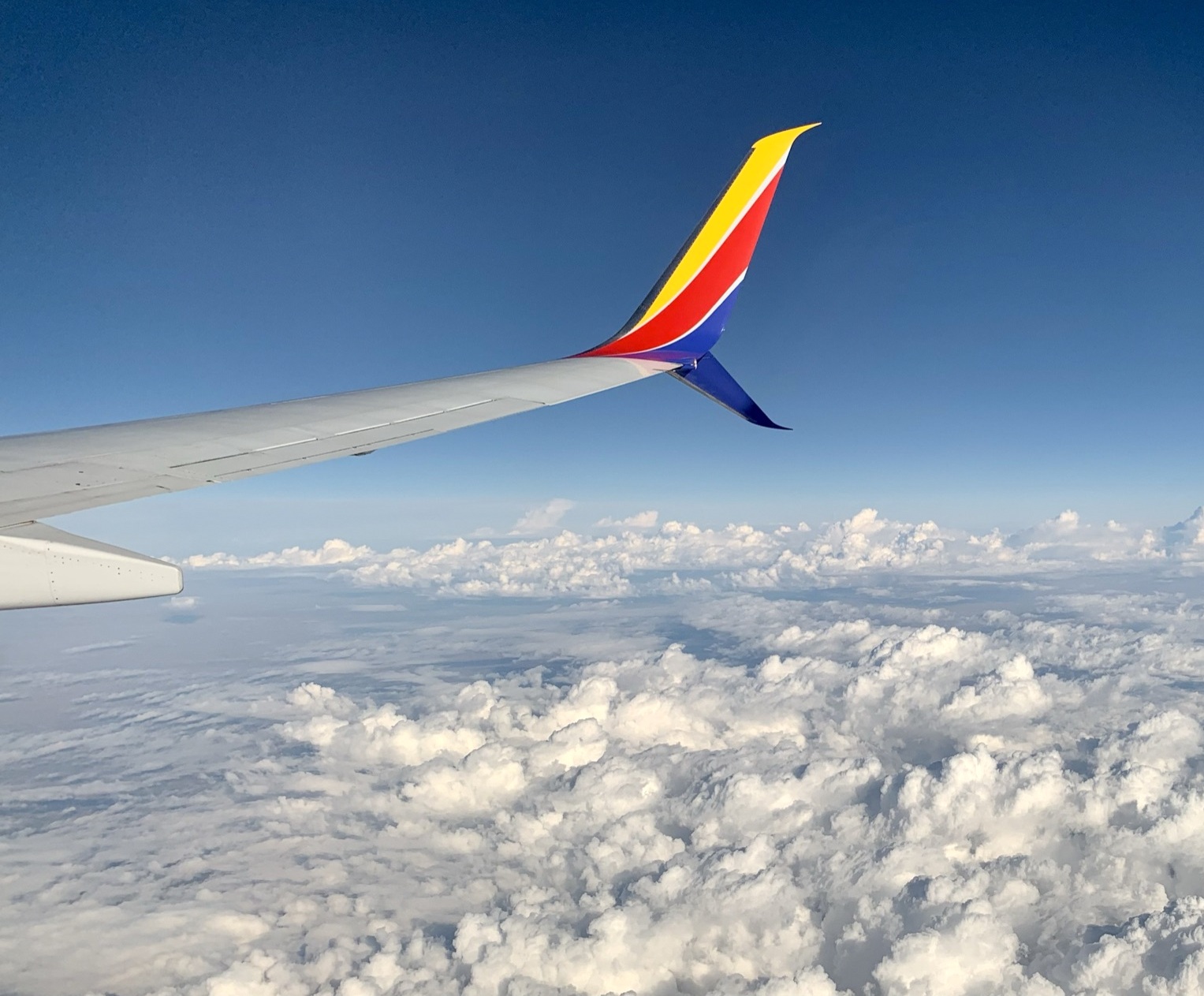 A view of an airplane wing and sky from a passenger seat window